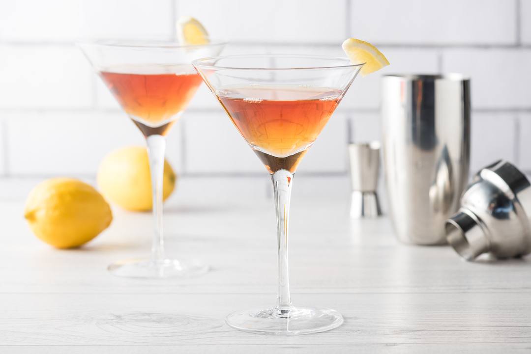 Fresh home made Manhattan cocktails with lemon and maraschino cherry